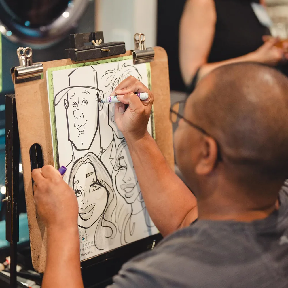 Adam Street drawing a live caricature of three guests at an Arizona Wholesale Appliance and Electrolux event
