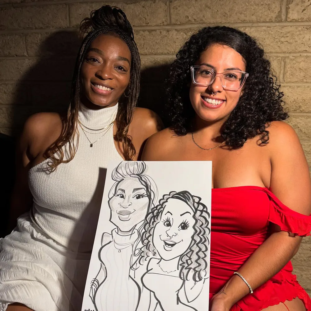 Two friends in party dresses beaming as they hold their Adam Street caricature