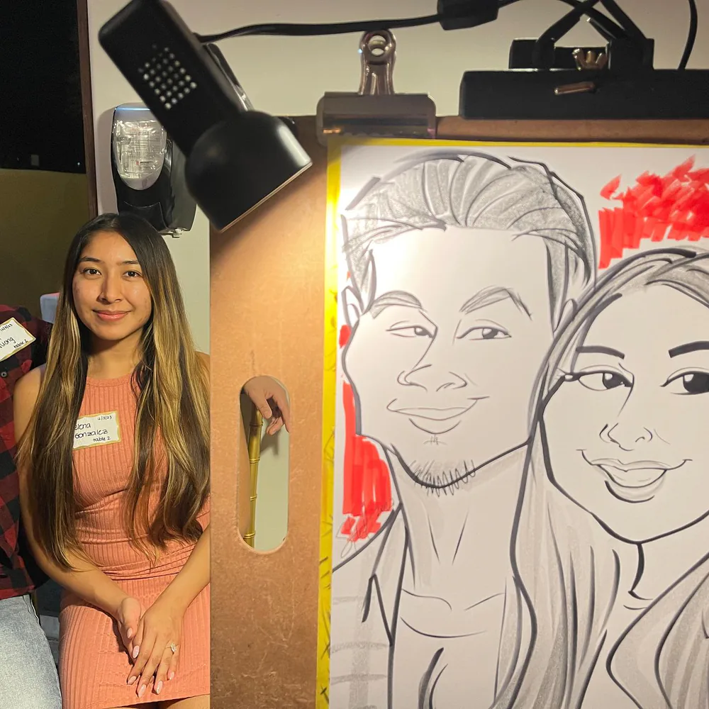 Event guest with a name tag smiling beside her Adam Street caricature under the easel lamp