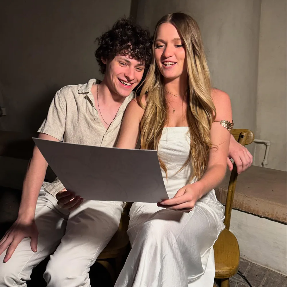 Young couple dressed in white grinning at their new Adam Street caricature