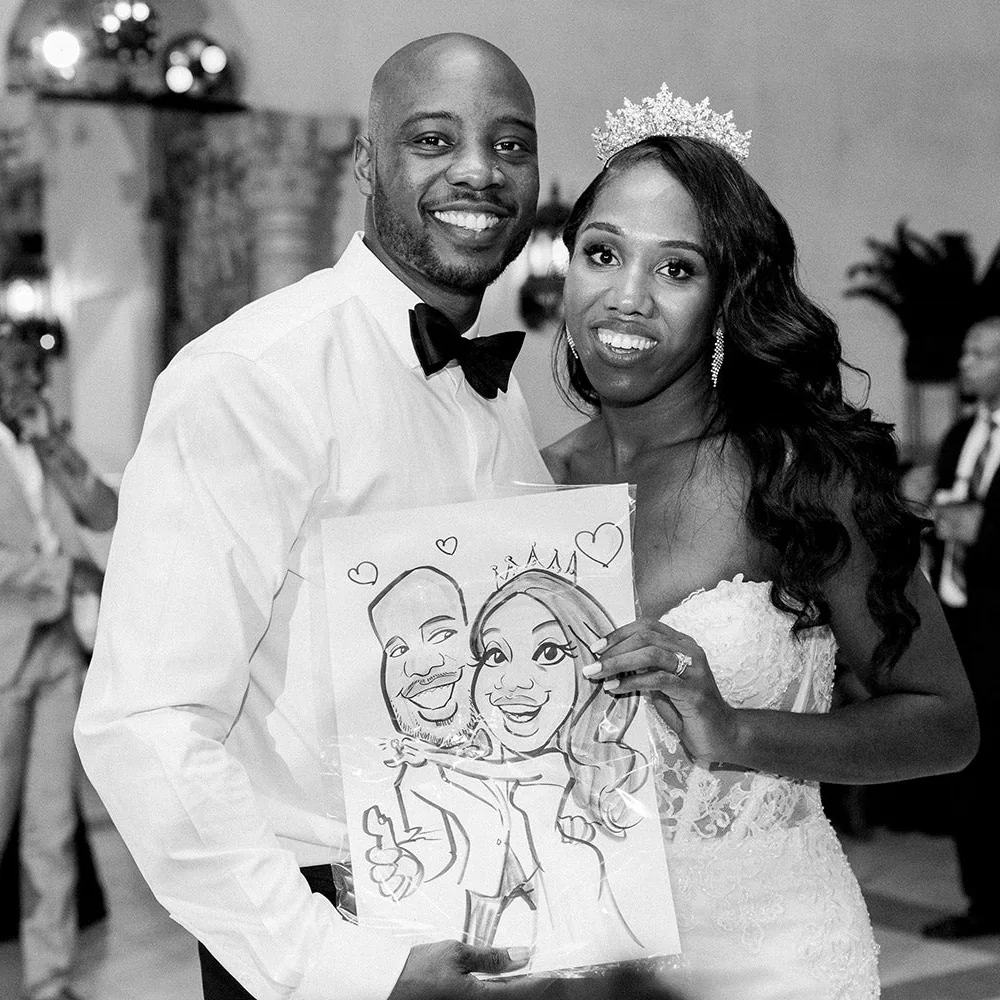 Bride in a crown and groom in a bow tie proudly holding their Adam Street caricature at the reception